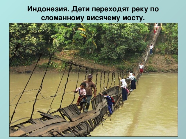 Индонезия. Дети переходят реку по сломанному висячему мосту.   