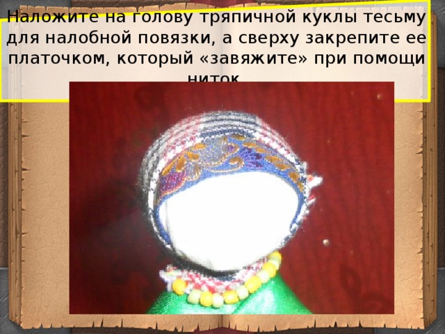 Наложите на голову тряпичной куклы тесьму для налобной повязки, а сверху закрепите ее платочком, который «завяжите» при помощи ниток.